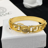 Medusa Aeterna Bracelet. Bold. Timeless. Captivating. This striking cuff features the iconic Medusa medallion centered between the legendary Greek Key motif. Crafted from durable stainless steel and richly plated in 21k gold.