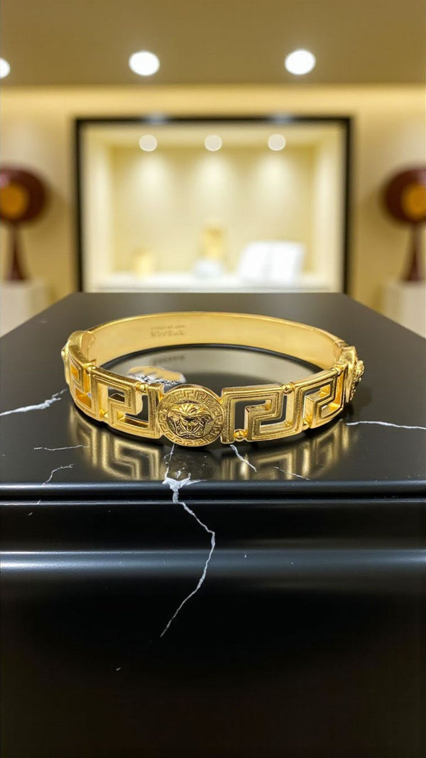 Medusa Aeterna Bracelet. Bold. Timeless. Captivating. This striking cuff features the iconic Medusa medallion centered between the legendary Greek Key motif. Crafted from durable stainless steel and richly plated in 21k gold.